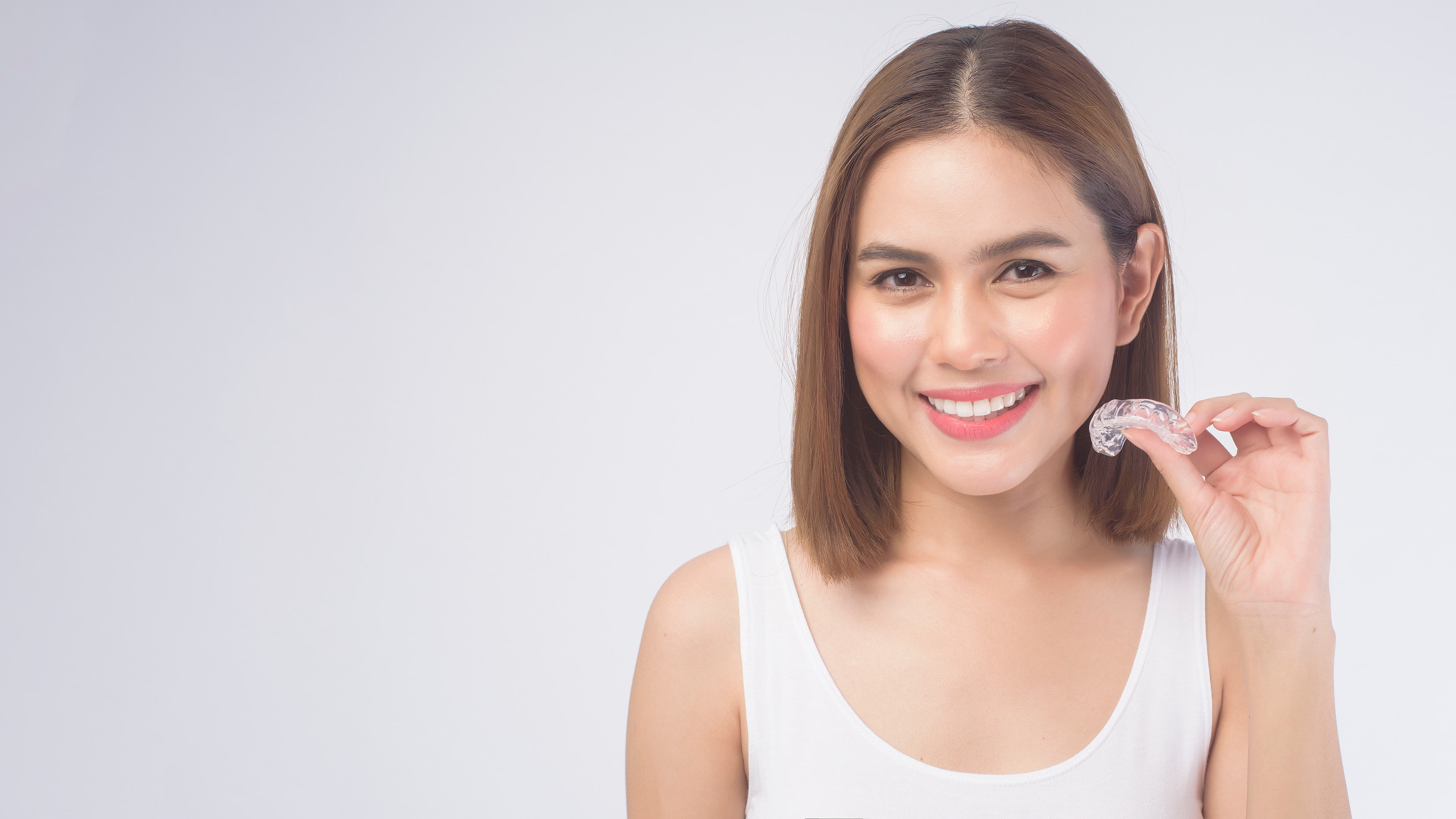 Patient holding a clear aligner — Invisalign at Dr. Soto The Downey Dentist